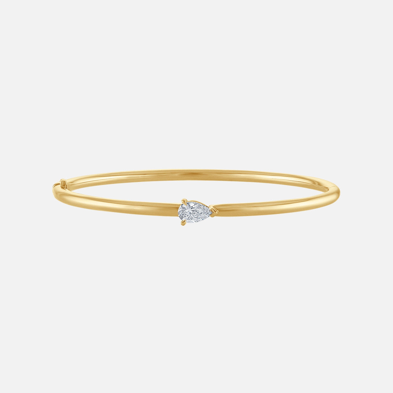 A gold bangle with a pear-shaped diamond in the center