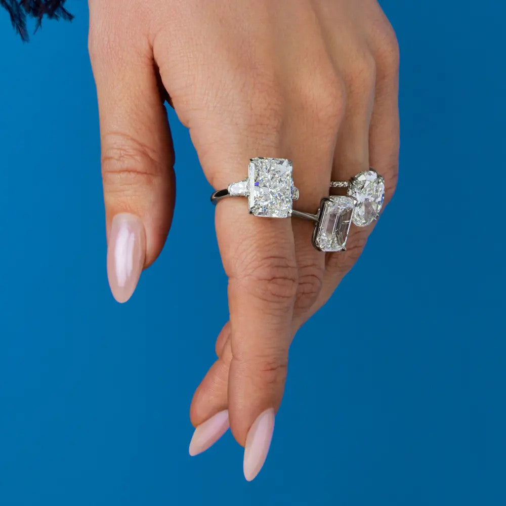 This platinum three-stone ring showcases a 10.19-carat radiant-cut diamond as its focal point. Enhancing the central stone are two tapered baguette diamonds, which together weigh 1.05 carats.