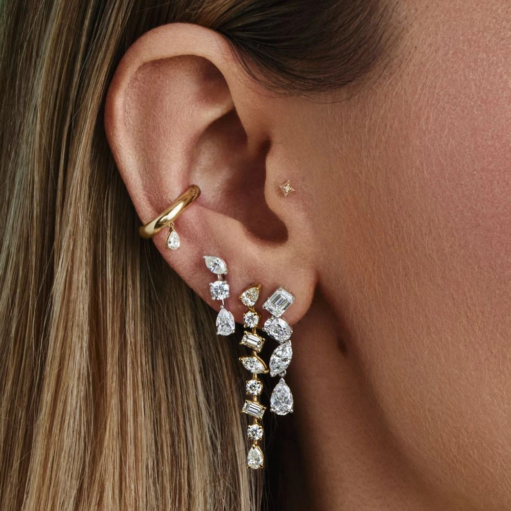 A woman wears diamond earrings, including an ear cuff with diamond dropping down