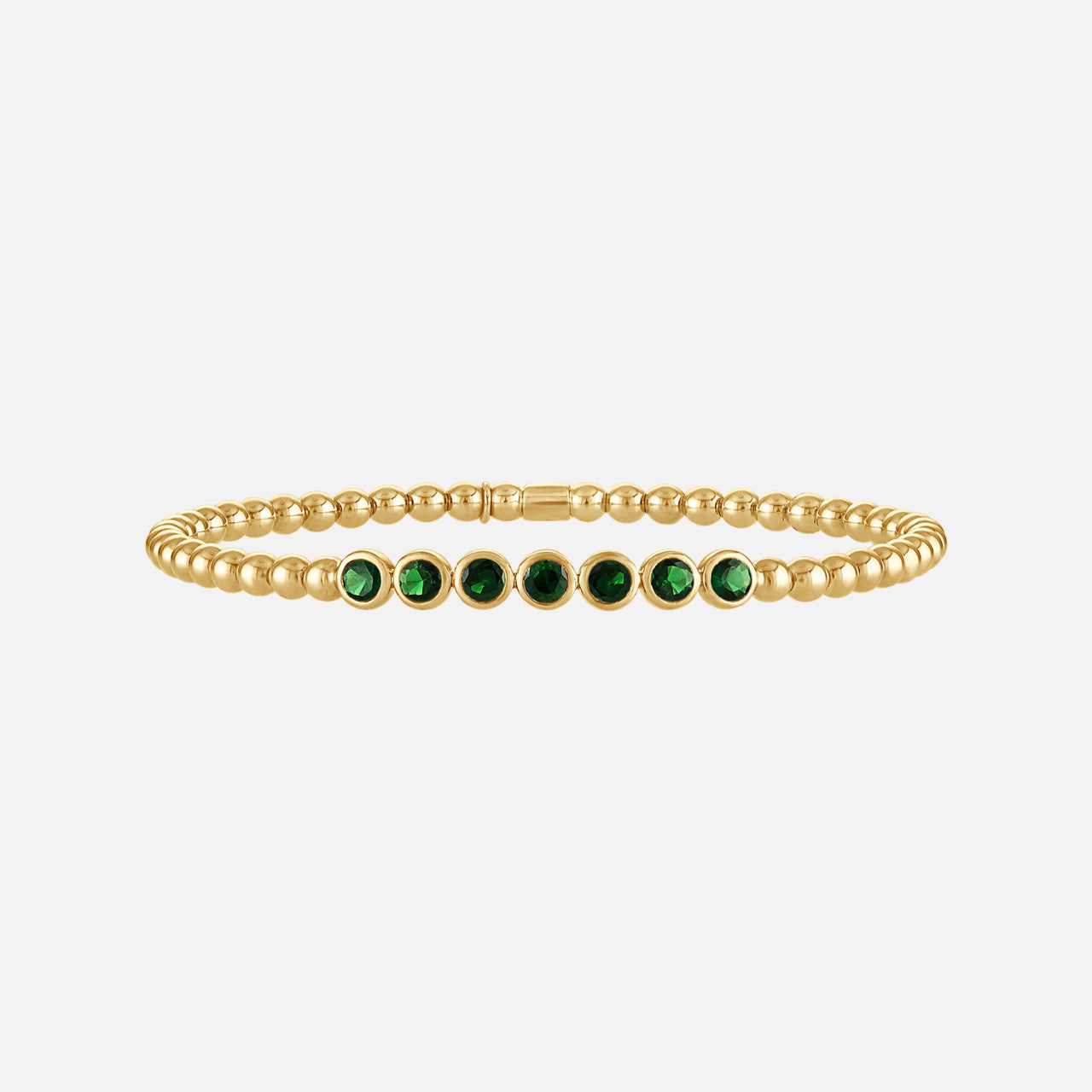 a gold beaded stretch bracelet with tsavorites in the center